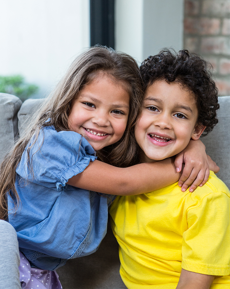 Cute siblings hugging on the sofa in living room